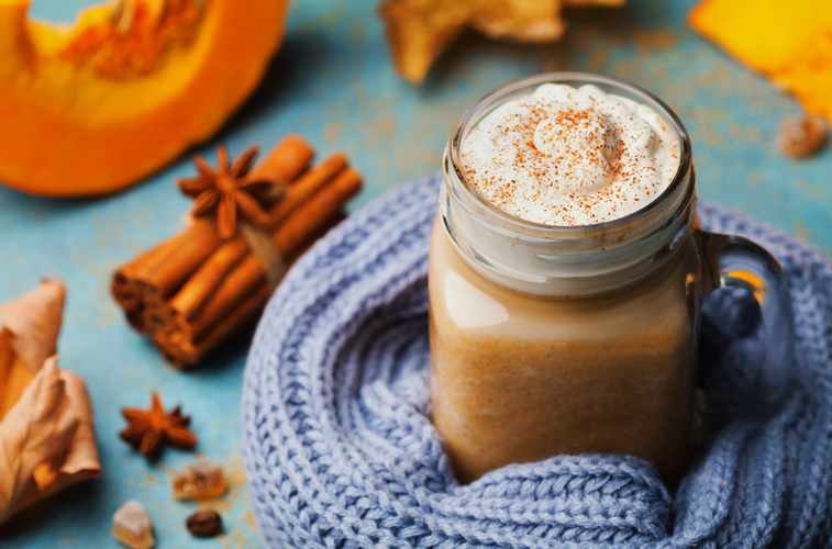 pumpkin shake in cup decorated knitted scarf on turquoise vintage background