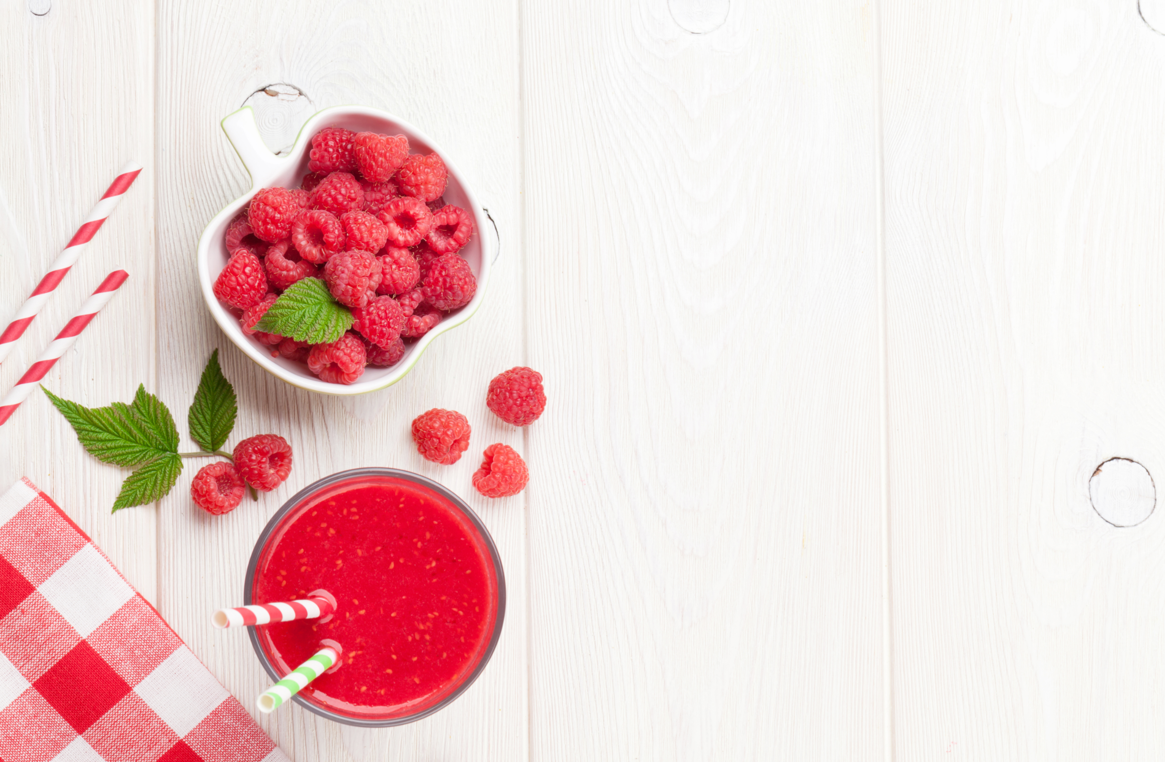 Raspberry smoothie and berries in bowl on wooden table