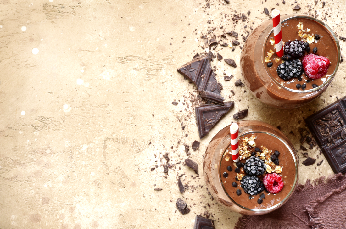 Two portion of chocolate banana smoothie in a glasses on a beige (sand) slate, stone or concrete background