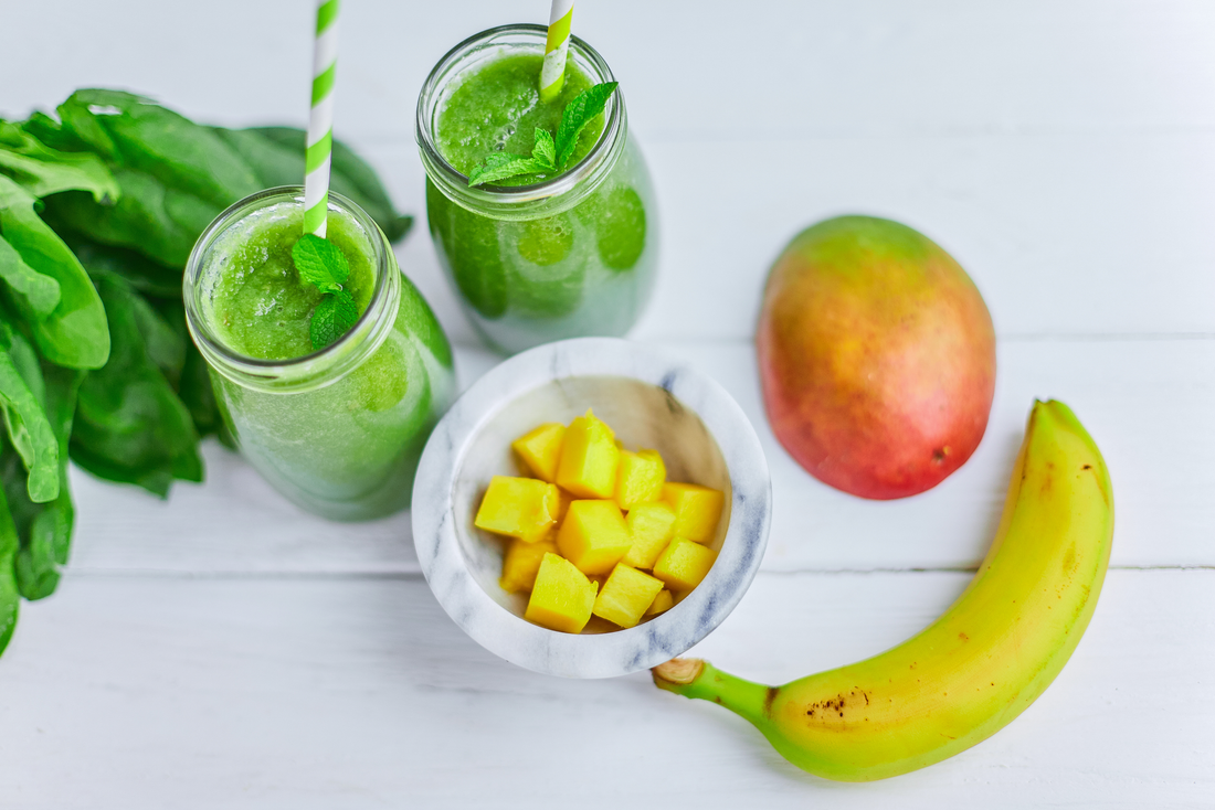 Mango with Banana and Spinach smoothie on white wooden table