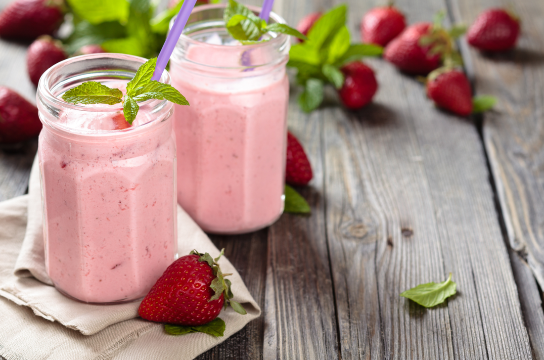 two glasses of strawberry jelly shake and fresh strawberries on a wooden surface