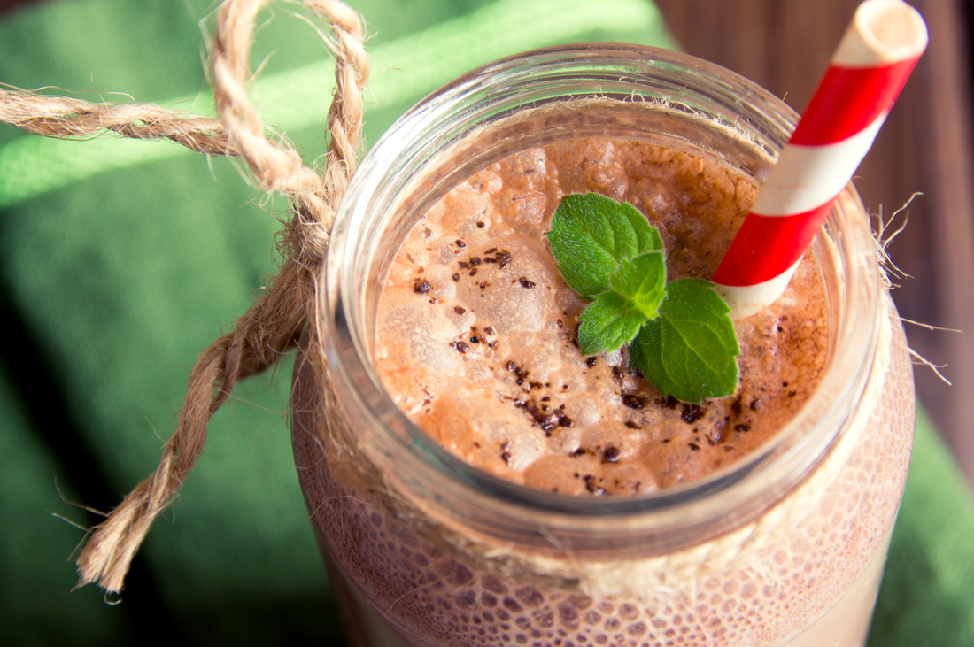 Chocolate smoothie (milkshake) with mint and straw in jar on dark wooden table