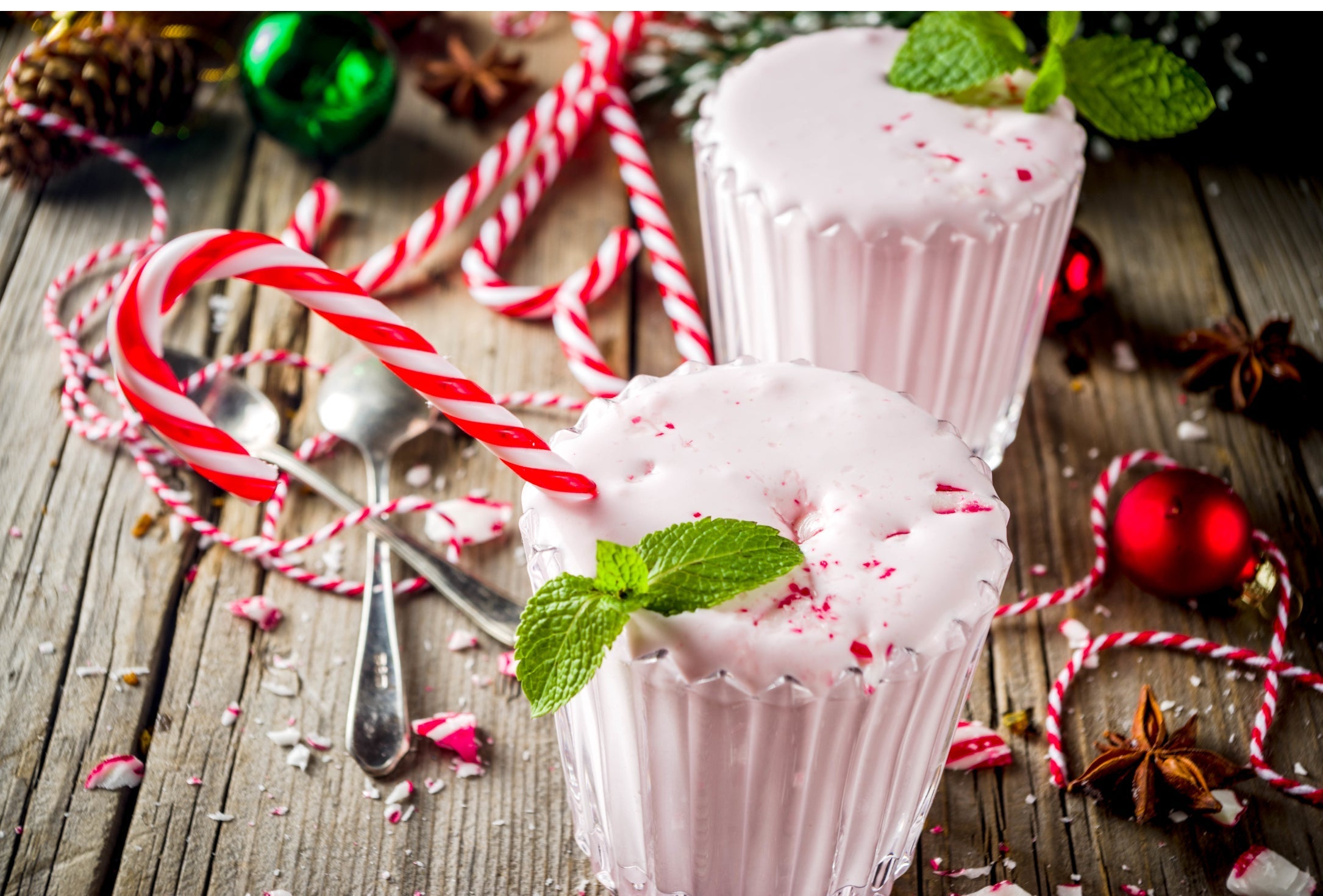 two peppermint keto shake with festive decorations on a wooden surface
