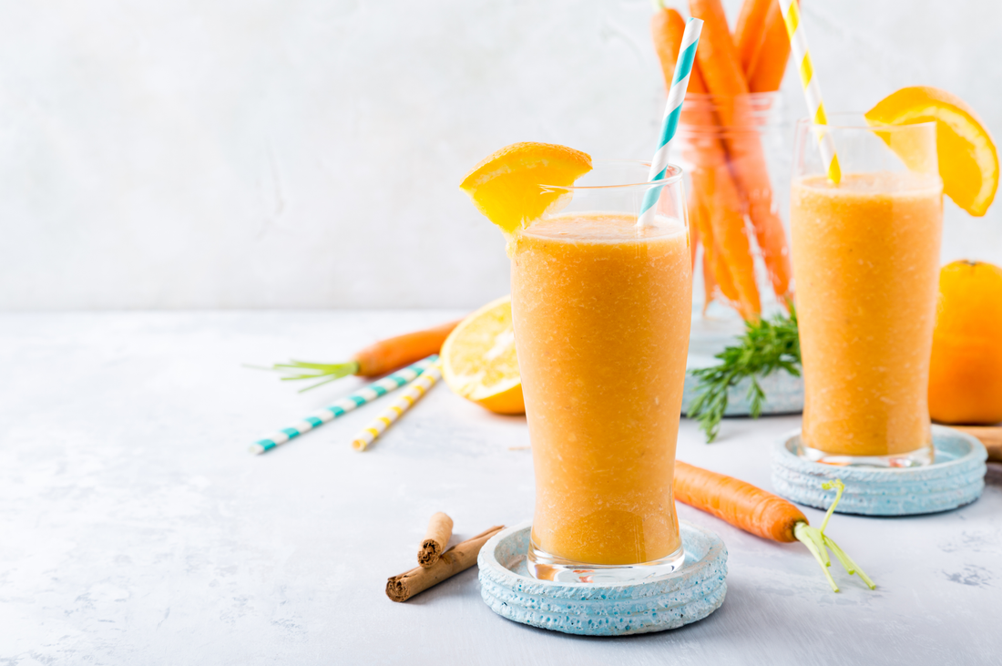 two glasses of tropical turmeric immunity boost shake and  fresh carrots