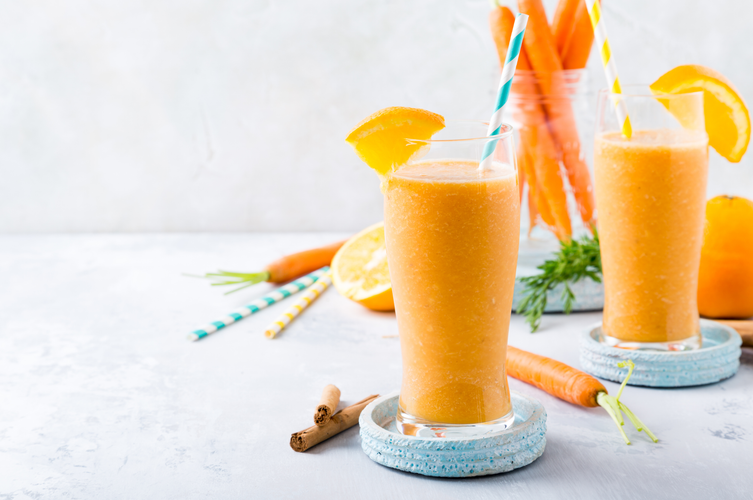 two glasses of tropical turmeric immunity boost shake and  fresh carrots