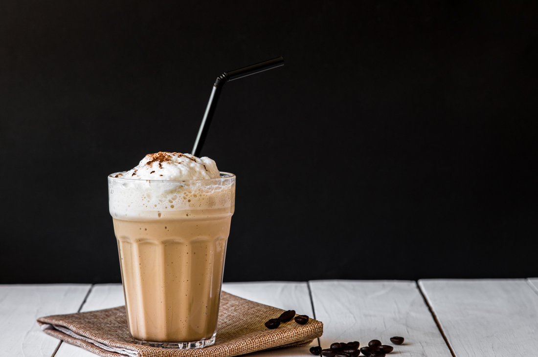blended of Iced coffee on cup and Roasted coffee beans on white wood background
