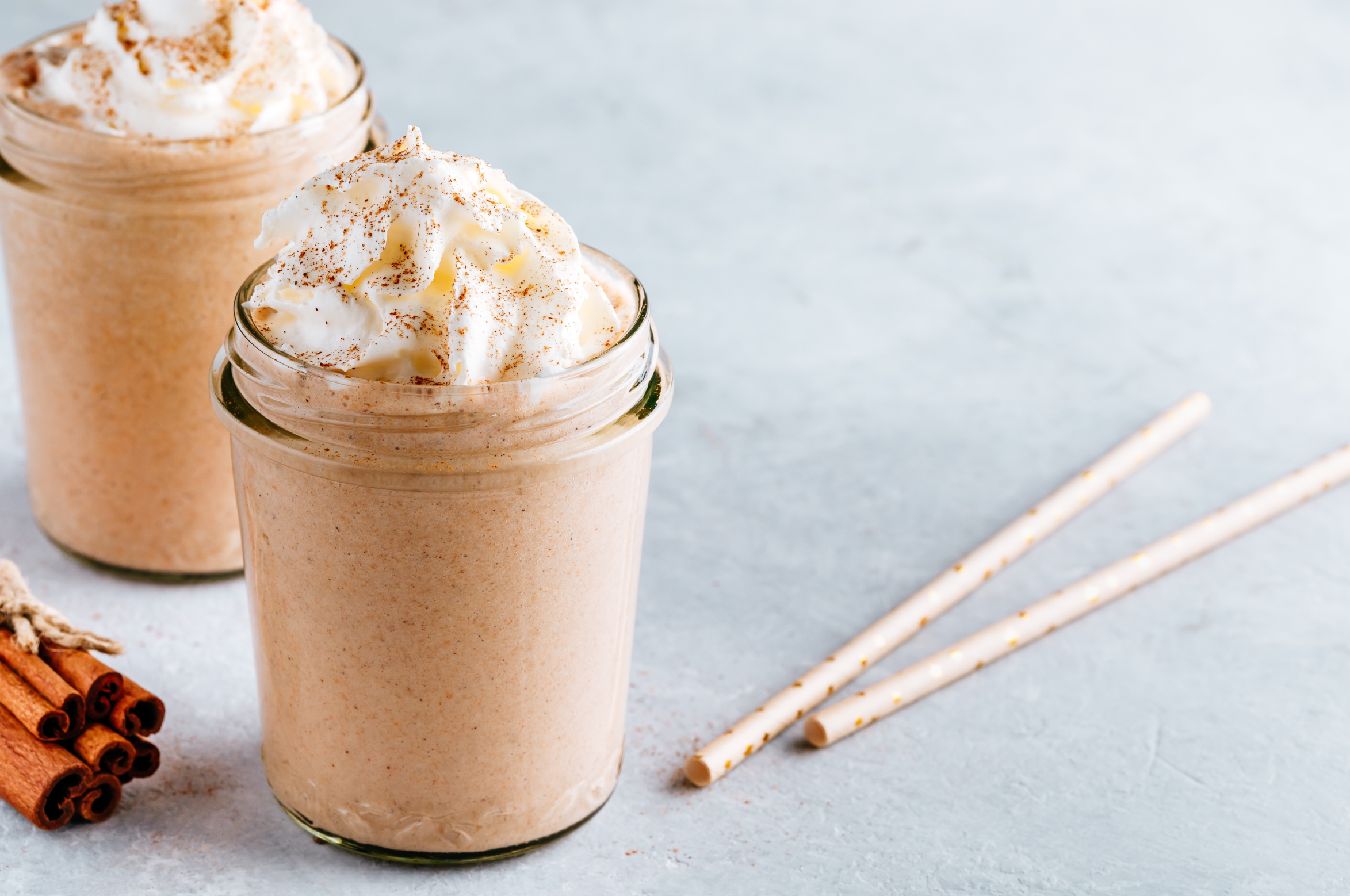 vanilla banana cinnamon smoothie with whipped cream in mason jars