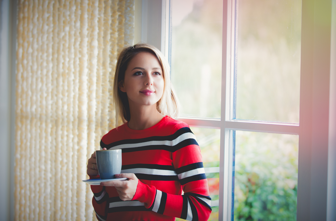 girl with cup of coffee stay near window at home