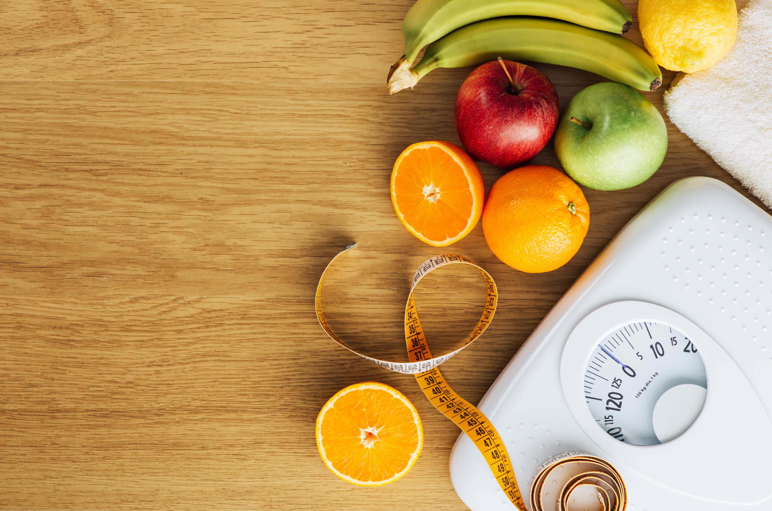 digital scale, measuring tape and fruits on a wooden table