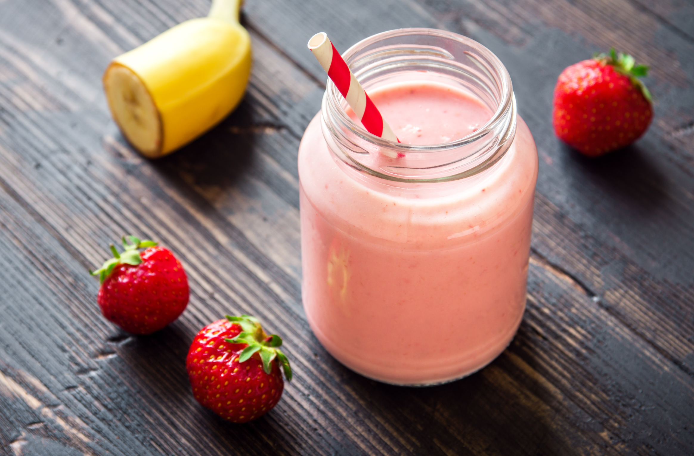 Strawberry and banana smoothie on rustic wooden background