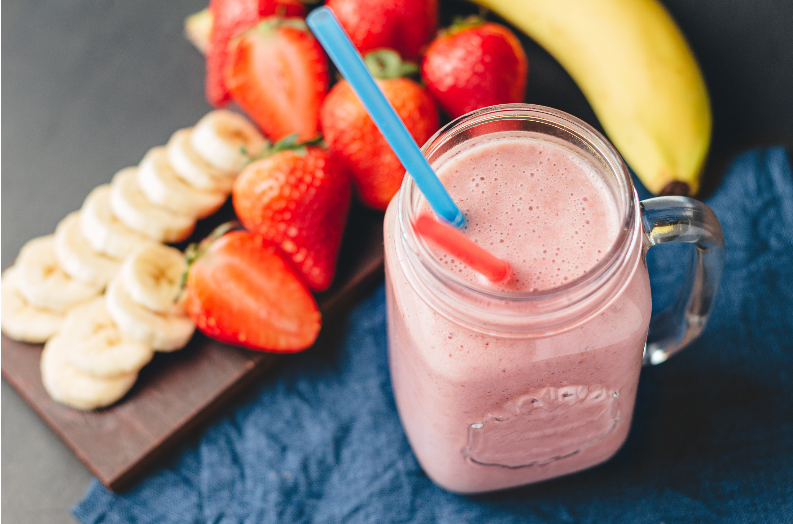 Smoothie with strawberry and banana in the jar at dark background