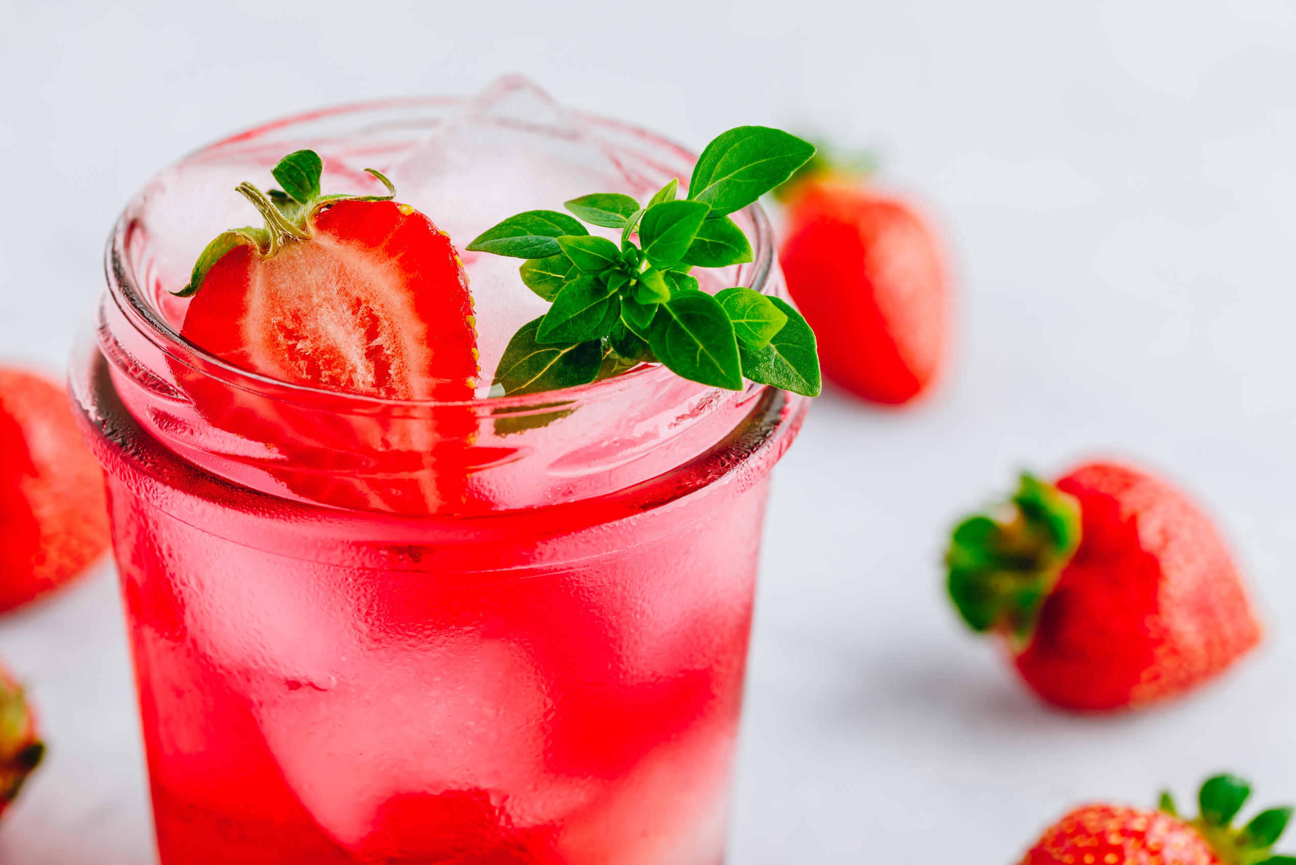 A glass of Strawberry Basil Lemonade and fresh strawberries