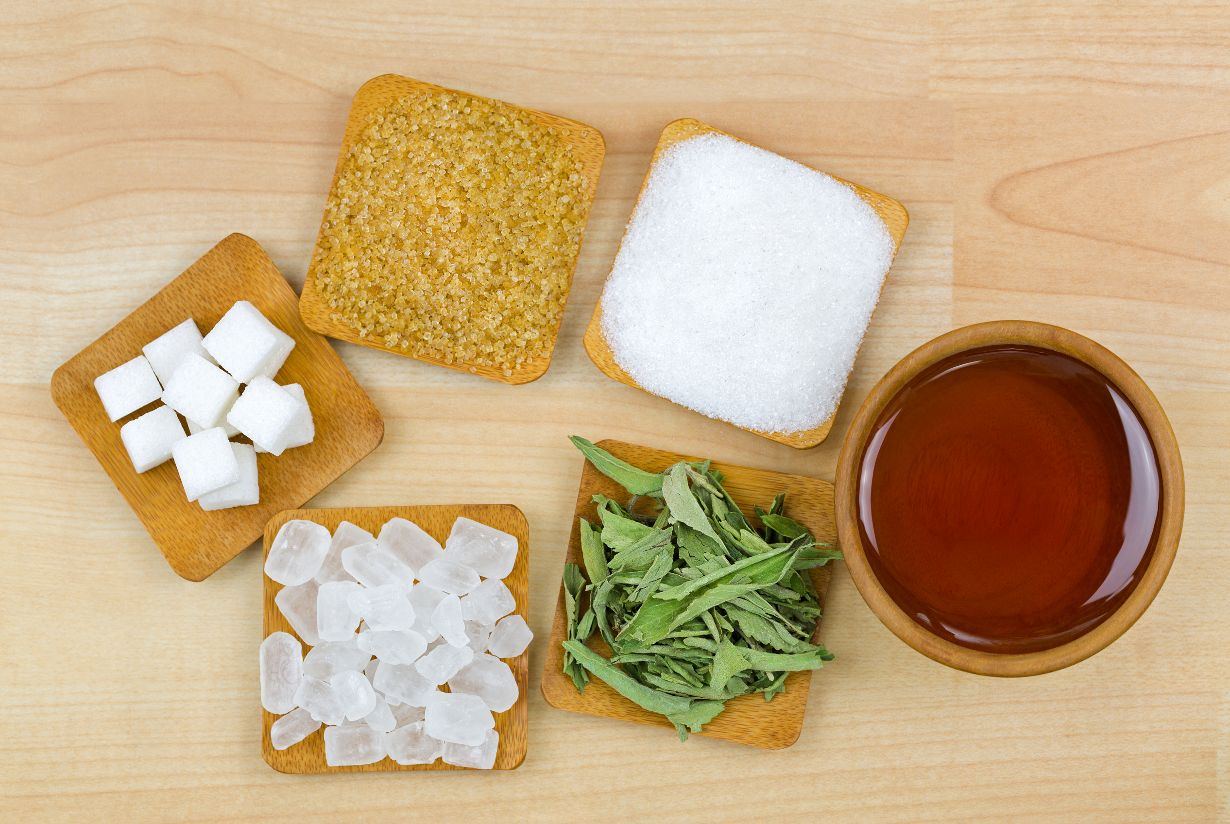 different kind of sweeteners on a wooden plate and bowl