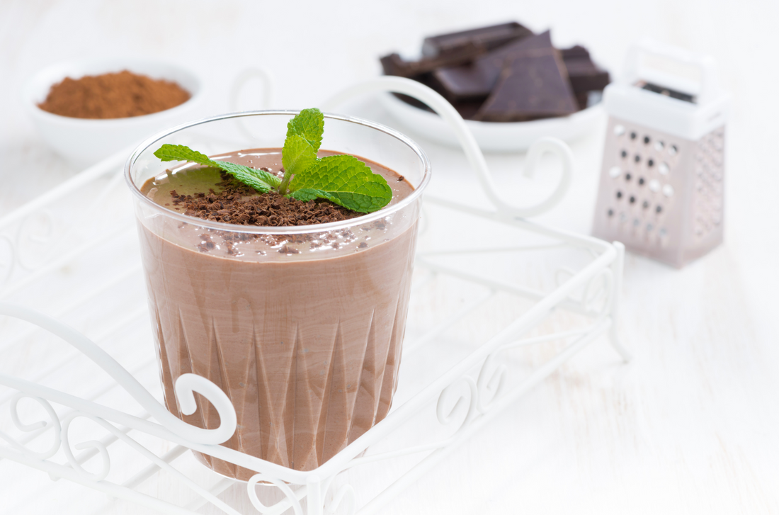 a glass of chocolate shake topped with mint leaves