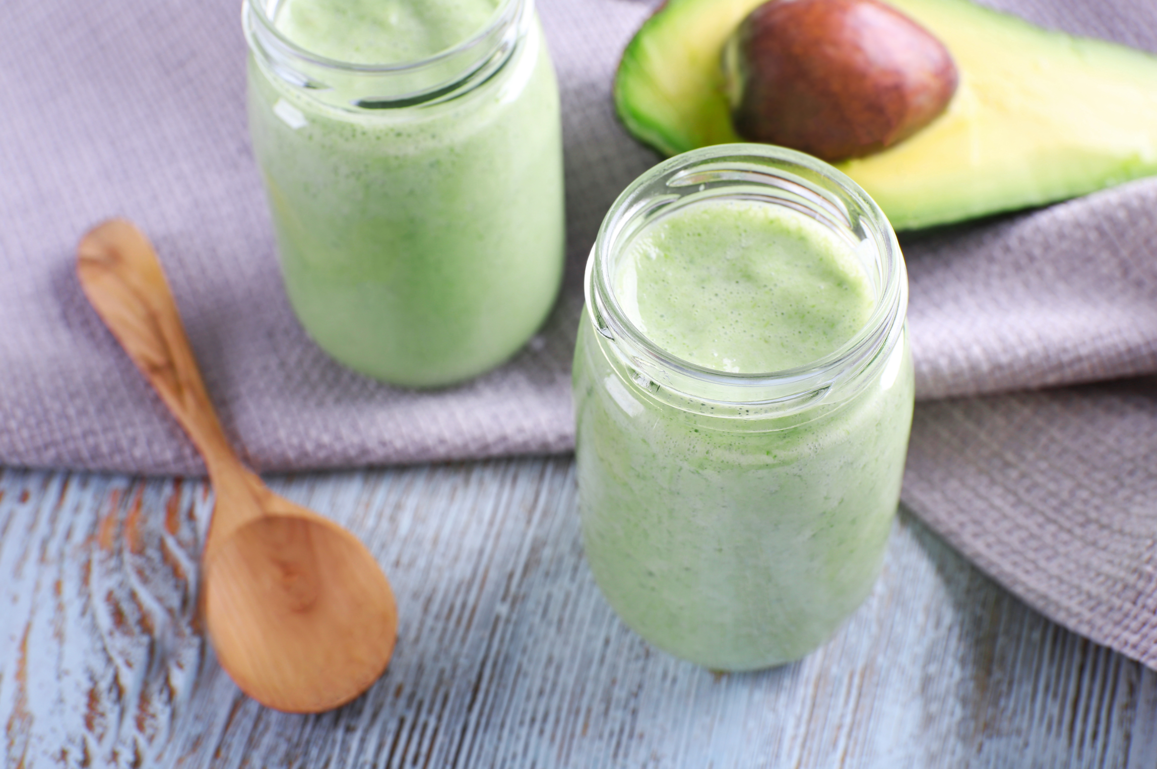 Avocado smoothie on wooden table with napkin closeup