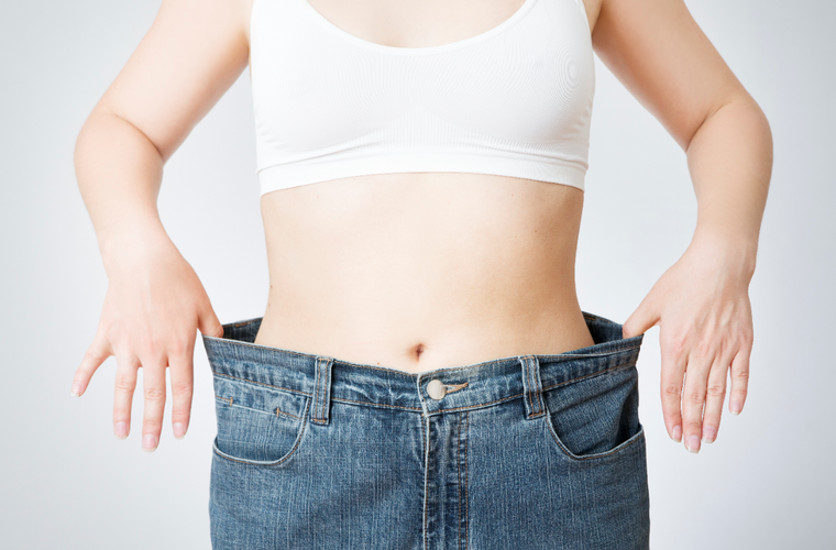 woman wearing loose jeans showing weight loss progress