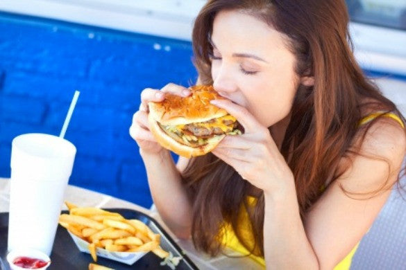 woman eating burger with fries and drinks on the table