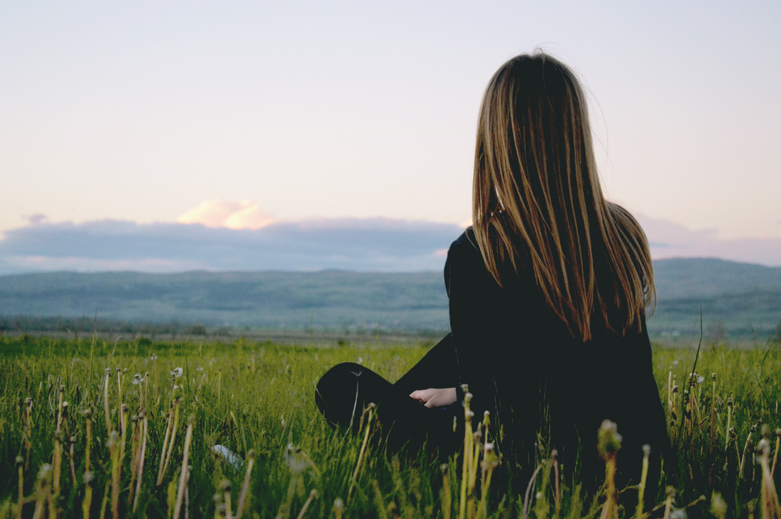 back of woman sitting in a green field