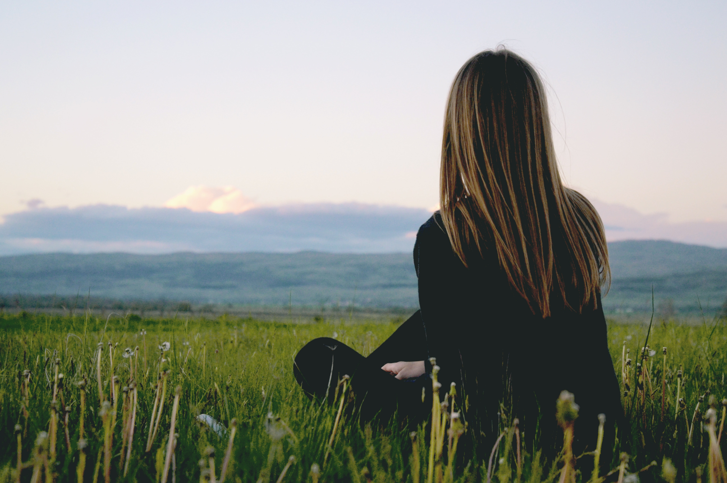 back of woman sitting in a green field