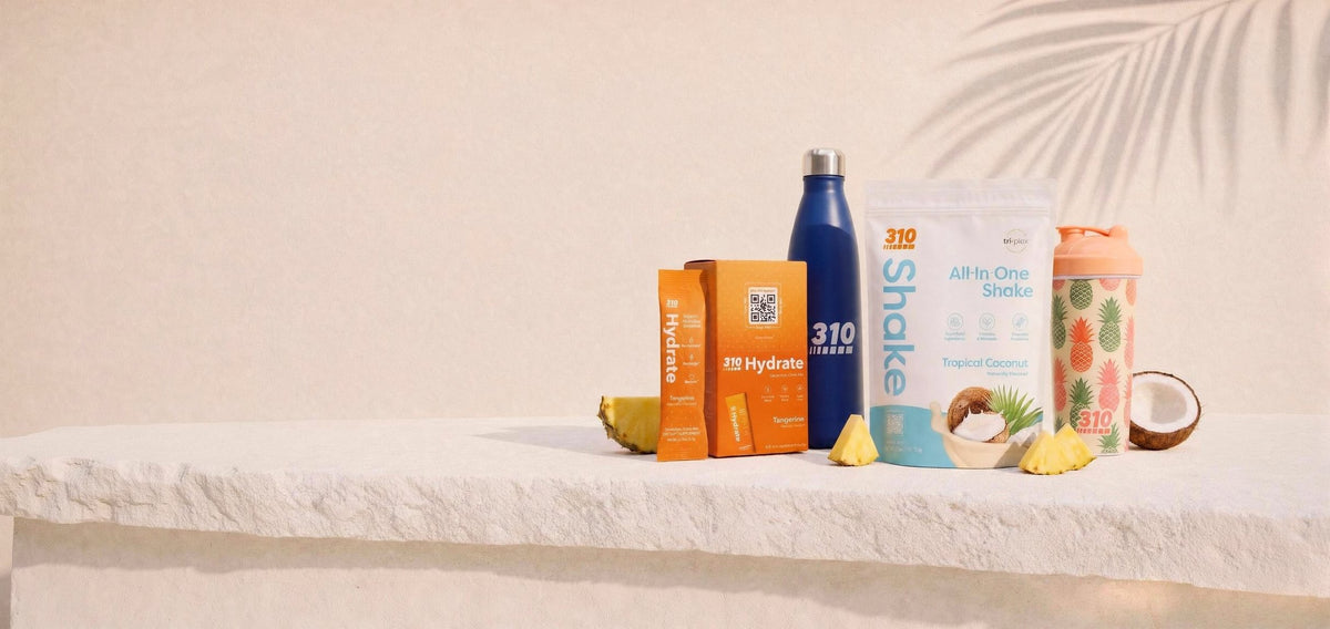 The Island Hydration Kit: Tropical Coconut shake, Hydrate Tangerine, navy 310 bottle and pineapple shaker on a stone ledge