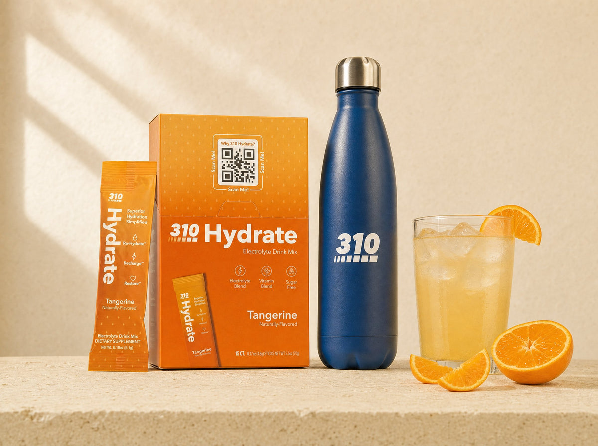 310 Hydrate Tangerine box and stick pack with the navy 310 bottle and a glass of Hydrate