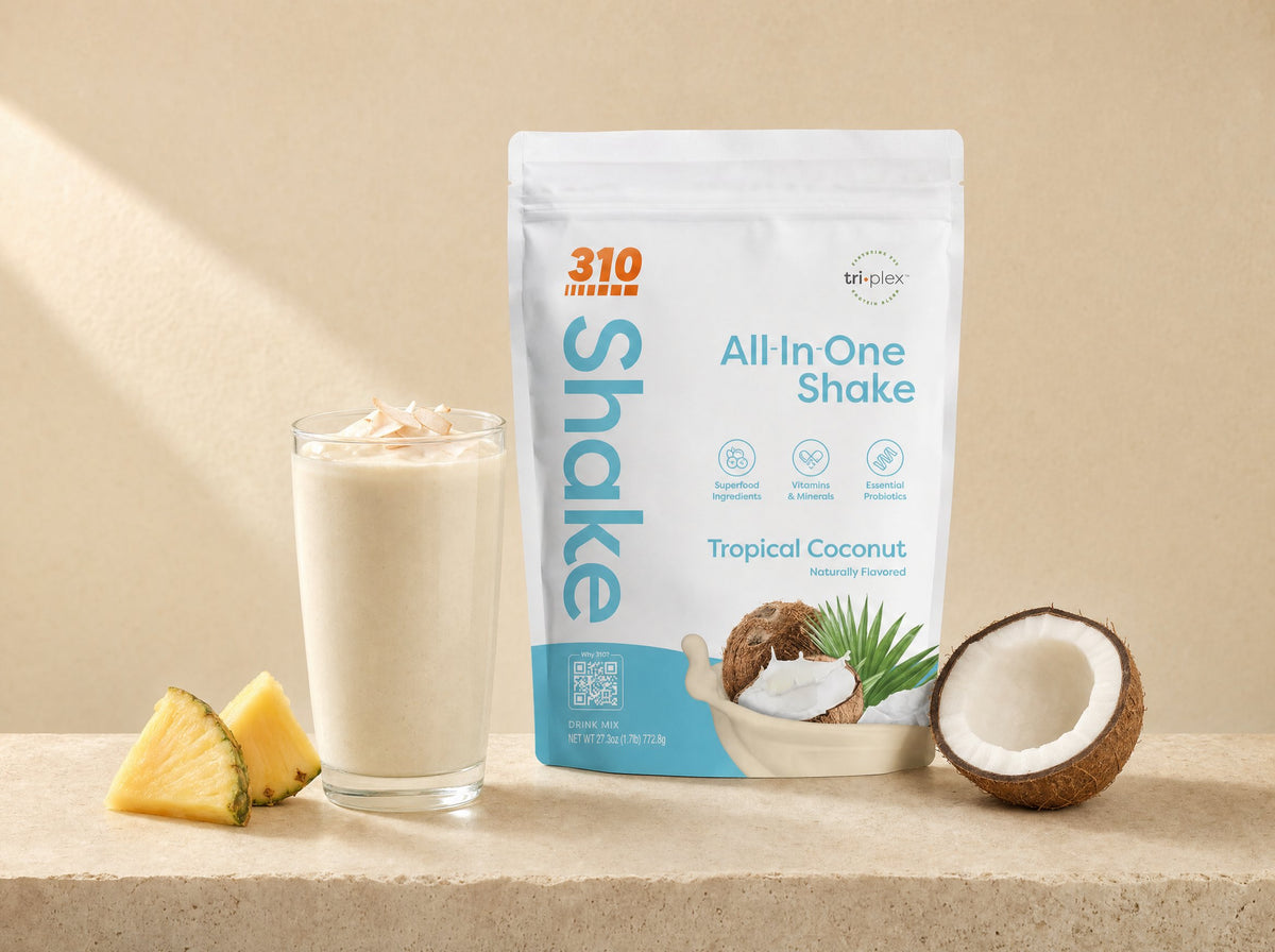 310 Tropical Coconut shake pouch next to a glass of coconut shake, pineapple and coconut