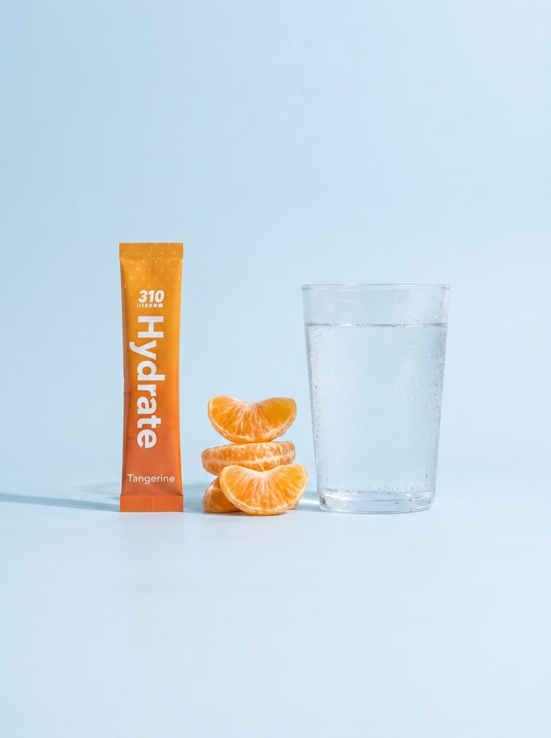 310 Hydrate Tangerine stick beside tangerine segments and a glass of water