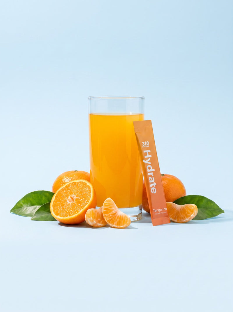 Glass of tangerine hydrate surrounded by fresh tangerines and leaves