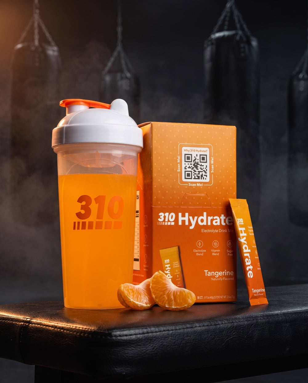 310 Hydrate Tangerine box, filled 310 shaker and stick on a dark ring-side bench