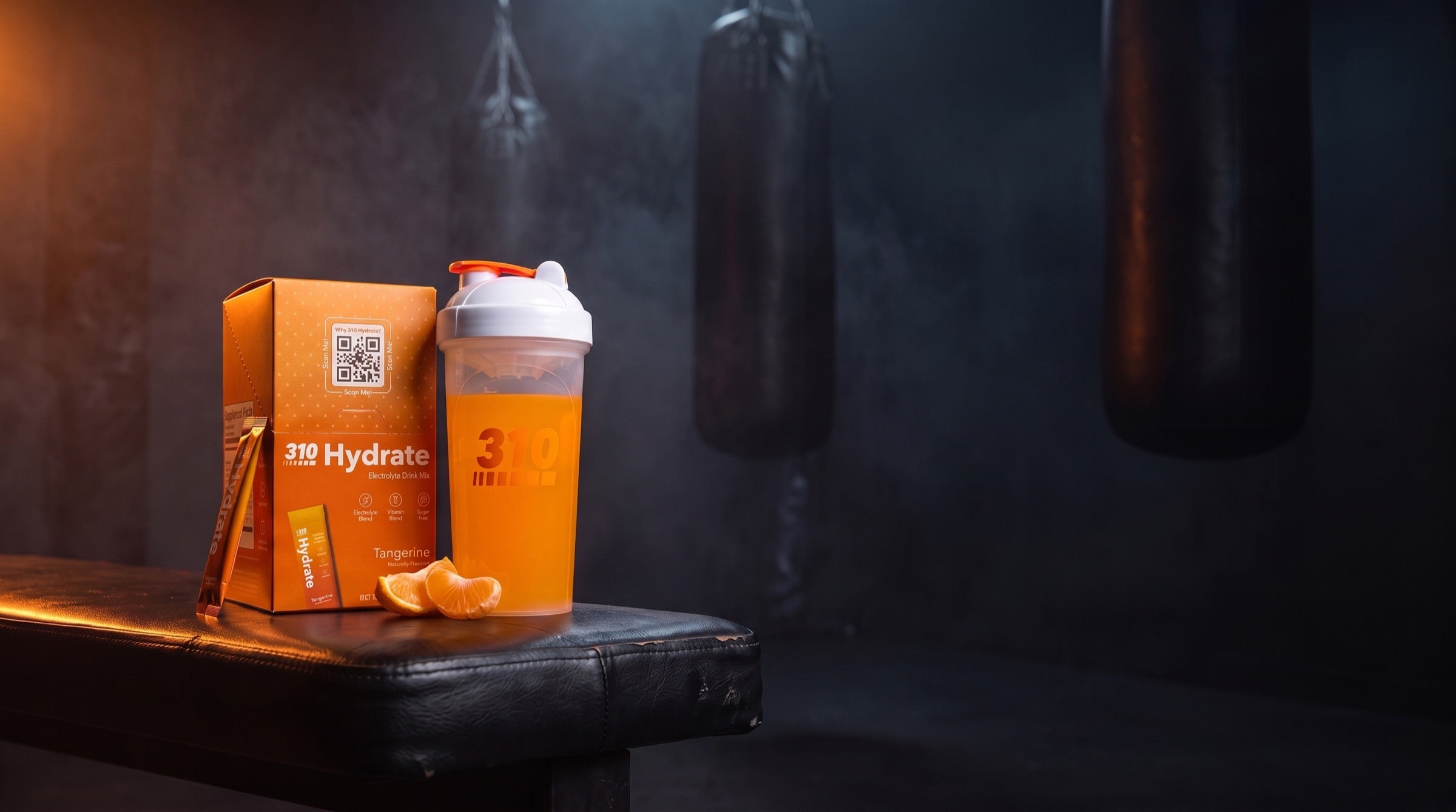 310 Hydrate Tangerine box, filled 310 shaker and stick on a dark ring-side bench