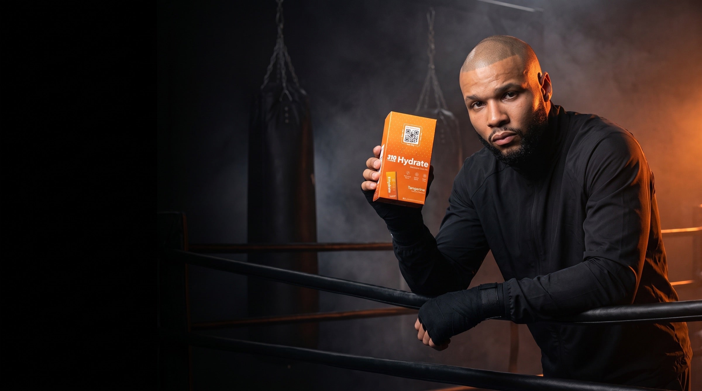 Chris Eubank Jr leaning on the ring ropes holding the 310 Hydrate Tangerine Eubank Jr Edition box