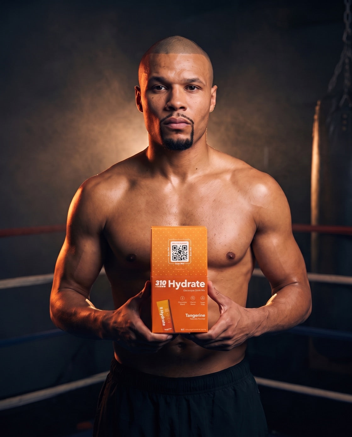 Chris Eubank Jr leaning on the ring ropes holding the 310 Hydrate Tangerine Eubank Jr Edition box