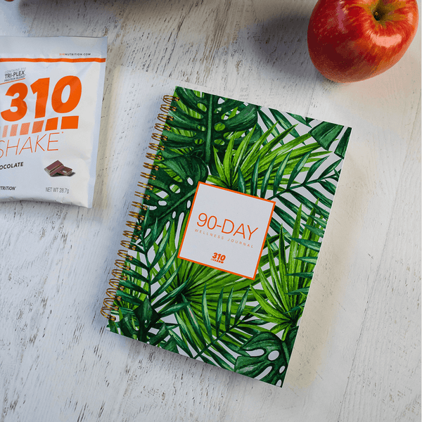 90-day wellness journal, chocolate shake and an apple on a wooden table