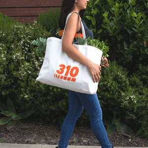 a woman wearing black top and jeans using the canvass tote bag