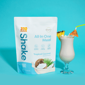 310 Tropical Coconut Shake pouch alongside a glass of tropical shake topped with pineapple.