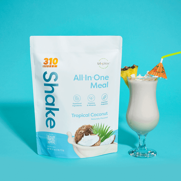 310 Tropical Coconut Shake pouch alongside a glass of tropical shake topped with pineapple.