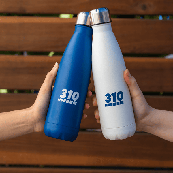 Two hands holding a 310 Hydration bottle in midnight blue and cool white colors.