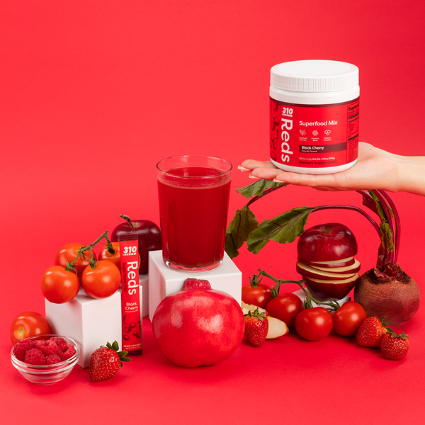 berries, beets, tomatoes, a glass of juice and hand holding 310 Reds Black Cherry flavor 