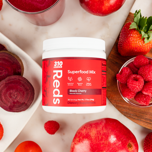 Overhead view of 310 Reds Black Cherry flavor with fresh berries, apples and a glass of juice.