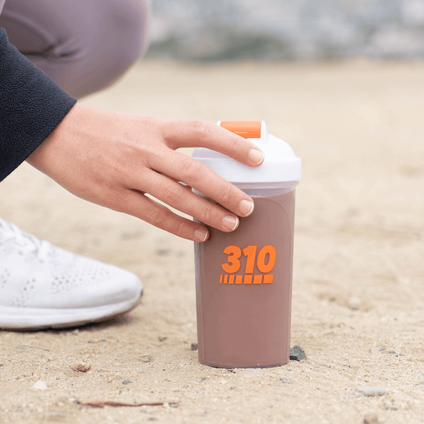 310 chocolate shaker cup on the ground with a hand holding it