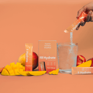 310 hydrate peach-mango, fresh mangoes and a glass of water