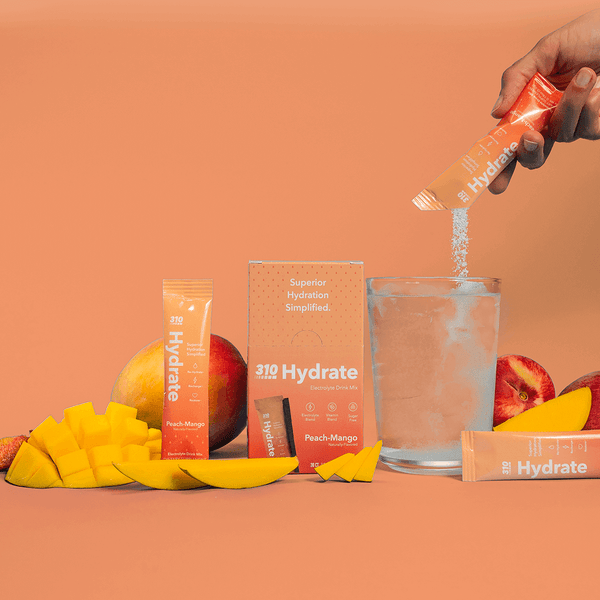 310 hydrate peach-mango, fresh mangoes and a glass of water