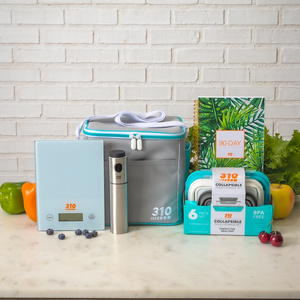 A teal 310 Meal Prep Bundle on a marble countertop, surrounded by fresh fruits and veggies.