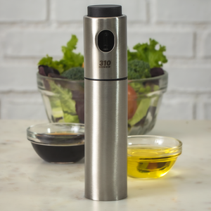 310 Oil Sprayer next to soy sauce and oil, with a large bowl of fresh vegetables.