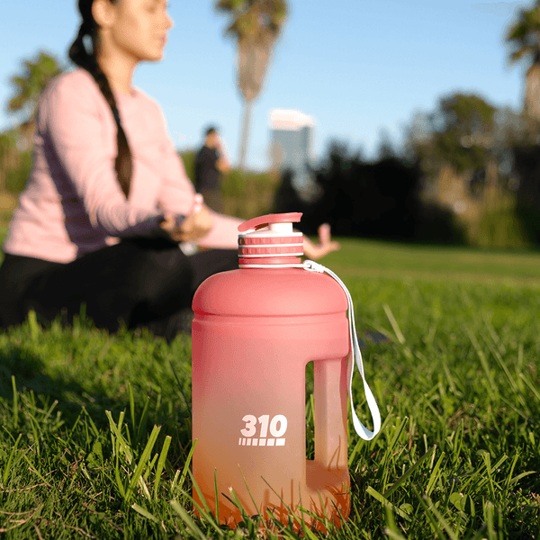 woman doing yoga with her sunset mega hydration bottle